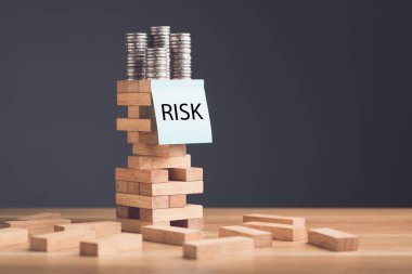 İş ve finansal konulardaki riskler. Ticarette riski önlemek için bir fikir. Üzerinde RISK sopa yapıştırıcısı yazan kağıt notlar. Ofisteki ahşap masa üzerindeki kule tahta blok oyununa. Stüdyo çekimi.