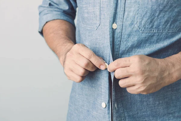 Man Buttoning Blue Jeans Shirt Studio Shot Grey Wall Background — Stock Photo, Image