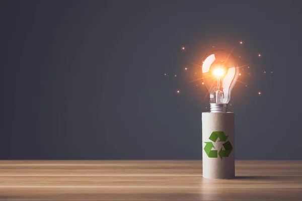 Create new ideas to recycle. Light bulb and pile of brown paper of tissue cores on wooden table with grey wall background. Save world and environment concept.