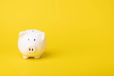 Finansal konsept, para biriktirme fikri, sarı renkli fotokopi alanı arka planında beyaz kumbarayı kapatma fikri. Tasarruf, Finans veya iş konsepti