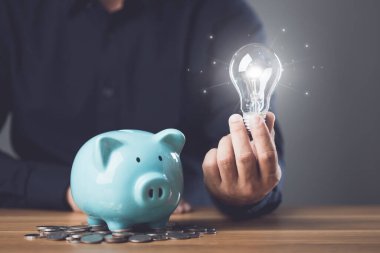 İş, Finansal ve Para Planlama, gelecek ve emeklilik için para biriktirmeyi düşünmek, Ampulü bozuk para ile tutan ve kumbaraya para ekleyen adam. Stüdyo çekimi.