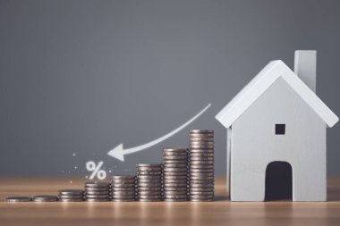 Konut için banka faizi, konut için faiz oranı, konut için iş ve finans, ev kavramı için para tasarrufu. Artan madeni para yığını ve ahşap masadaki ev modeli. Stüdyo çekimi.