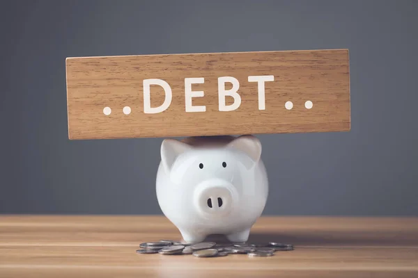 財務上の問題 破産またはビジネスコンセプトに失敗します 新しい貯金箱 コインスタックと単語の白 Debtは暗い壁の背景を持つ木製の机の上に木の板に書きます — ストック写真