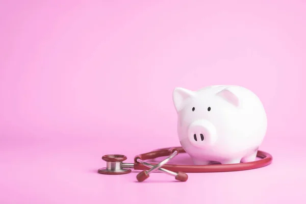 Financial health check, The idea of taking care of saving money, Man using stethoscope to check white piggy bank on desk with grey copy space background. Health and finance concept