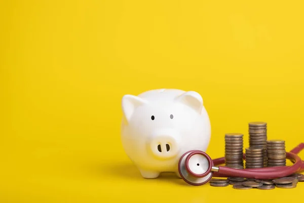 Financial for health concept, The idea of saving money for healthcare Close up stethoscope and white piggy bank on yellow color and copy space background. Health and finance concept