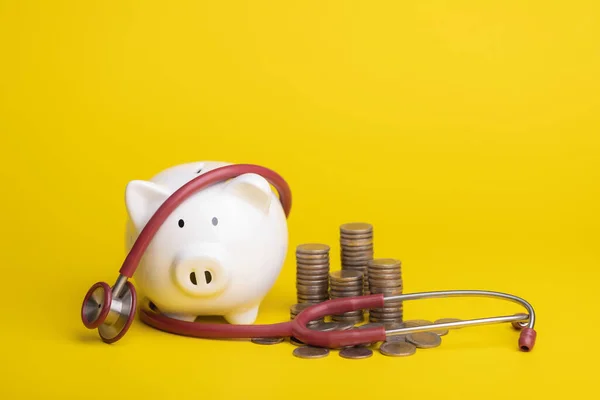 Financial for health concept, The idea of saving money for healthcare. Close up stethoscope and white piggy bank on yellow color and copy space background. Health and finance concept