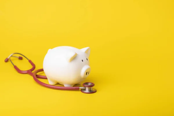 Financial for health concept, The idea of saving money for healthcare,Close up stethoscope and white piggy bank on yellow color and copy space background. Health and finance concept