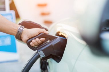 Elektrikli araba kullanma kavramları. Elektrikli araba kullanıcısı, elektrikli arabayı şarj etmek için siyah bir şarj aleti tutuyor. Elektrikli arabaların Tayland 'da en son alternatif enerji kaynağı olarak kullanılması.