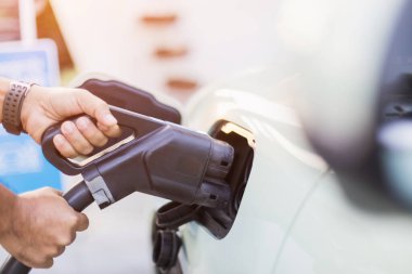 Elektrikli araba kullanma kavramları. Elektrikli araba kullanıcısı, elektrikli arabayı şarj etmek için siyah bir şarj aleti tutuyor. Elektrikli arabaların Tayland 'da en son alternatif enerji kaynağı olarak kullanılması.