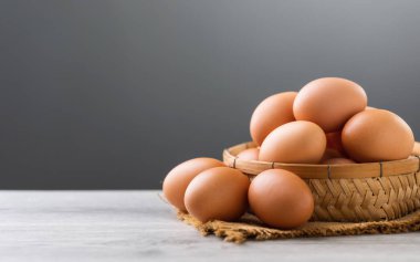 Yumurta sepeti gri arka planda bir masanın üzerine yerleştirilir. Görüntü, basitlik ve tazeliği, doğal bileşenleri ve sağlıklı, besleyici gıda fikrini sembolize ediyor.