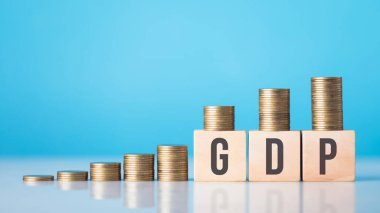 En küçükten en büyüğe sıralanmış bozuk paraların yanına 'GSYİH' etiketli tahta blok. Ekonomik büyüme kavramı ve bir ülkenin mali ilerlemesinin ölçülmesinde Gayri safi Yurtiçi Hasıla 'nın rolü