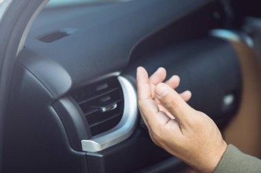 Araç sahibi, araç su altında kaldıktan sonra havalandırmanın serin havasını hissederek havalandırmayı kontrol ediyor. Araç bakımı kavramı, sel sonrası soğutma sistemi denetimlerine odaklanma
