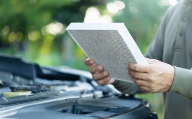 Bir araba sahibi muayene için bir hava filtresi tutar. Düzenli teftiş, temizlik ve araba hava filtrelerinin değiştirilmesi, hava kalitesi ve araç verimliliğinin artırılması için bakımı vurguluyor