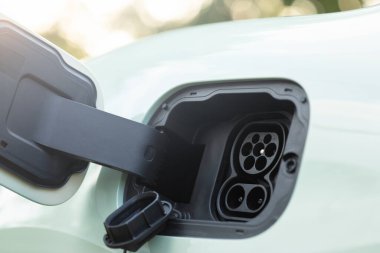 AC ve DC bağlantılarını gösteren, çok yönlü enerji çözümleri için çift şarj seçenekleri vurgulanan, açık elektrikli aracın yakın plan görüntüsü