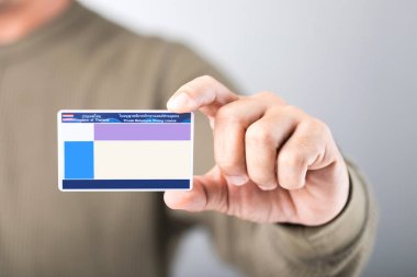 A Thai man holds a blank Smart Card Thailand driver's license, emphasizing the importance of obtaining a license for road safety and responsible driving clipart