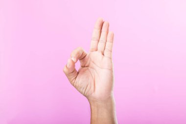 El, bir yumruk, açık avuç içi ve pembe arka plana karşı kaldırılmış parmaklar gibi çeşitli jestler sergiler. El sembolleri aracılığıyla iletişimin görsel keşfi