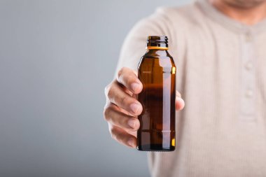 Bir adam elinde bir şişe enerji içeceği tutuyor ve bu da onun sağlığa olan etkisini sorguluyor. Enerjiyi artırıyor mu yoksa potansiyel dezavantajları mı var? Refah için bilinçli seçimler yapmanın bir yansıması.