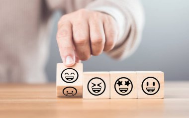 Wooden blocks displaying a sad face transitioning to a happy face, symbolizing a shift from negativity to positivity. Final block turns from sad to happy, highlighting the power of a positive outlook clipart