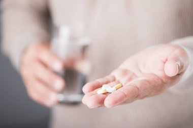 A man holding a glass of cold water and a pill, illustrating the common misconception of taking medication with cold water. Highlights the potential risks and importance of proper medication practices clipart