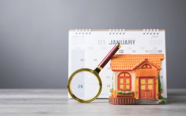 A 2025 calendar, house model, and magnifying glass on a table. The search for an auspicious date to move into a new home. This reflects the tradition of finding the perfect timing for a fresh start clipart