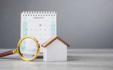 A 2025 calendar, house model, and magnifying glass on a table. The search for an auspicious date to move into a new home. This reflects the tradition of finding the perfect timing for a fresh start clipart