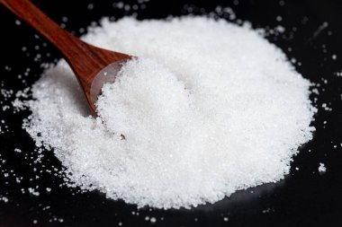 Tahta kaşıkta yakın plan beyaz şeker. Karanlık ve karamsar arkaplan.