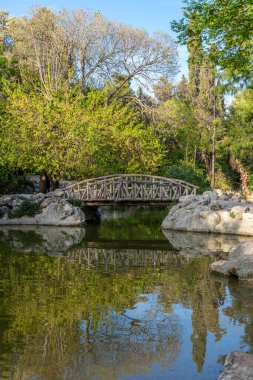 Yunanistan 'ın başkenti Atina' daki Ulusal Bahçe 'deki bir gölette tahta köprü ve yansıma.