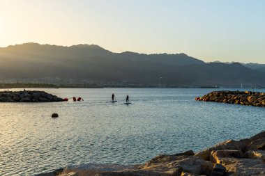 Eilat, İsrail 23 Eylül 2022 Kadınlar, gün doğumunda Akabe ve Ürdün dağlarından Kızıl Deniz 'i geçerek kürek çekiyorlar.