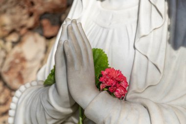 İsrail 'deki Carmel Dağı' ndaki Muhraqa Manastırı 'nın avlusundaki Bakire Meryem heykelinin çiçekleriyle dua eden elleri kapat..