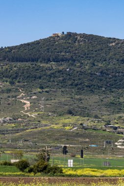 İsrail 'in kuzeyindeki Carmel Dağı tepesindeki Muhraqa Karmelite Manastırı güneşli bir günde İsrail' in Kfar Yehoshua kentindeki tren istasyonundan görülüyor..