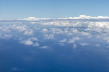 Pasifik Okyanusu 'nun maviliğine karşı beyaz bulutlar Hawaii Adaları yakınlarındaki bir uçaktan görüldü.