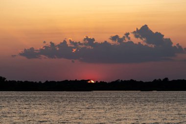 ABD 'nin Minnesota kentindeki Kuzey Kaplumbağa Gölü' nde Tanrı 'nın ışınları ve ağaçlarıyla turuncu yaz günbatımı.