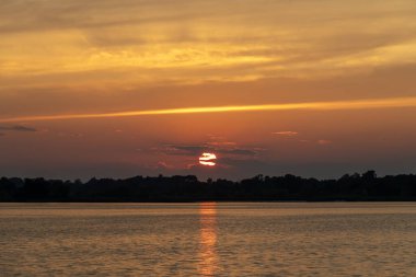 ABD 'nin Minnesota kentindeki Kuzey Kaplumbağa Gölü' nde bulutlu ve ağaçlı turuncu yaz günbatımı