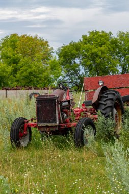 Minnesota, ABD kırsalında yeşil bir çayırda duran terk edilmiş eski traktör..