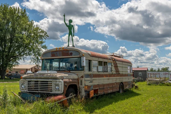 Milaca, Minnesota, ABD 29 Temmuz 2022 turuncu okul otobüsünde duran yeşil bir uzaylının heykeli ABD 'nin Minnesota, Milaca kentindeki bir antikacıda..