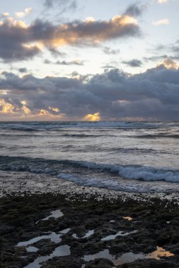 Sabahın erken saatlerinde Kauai, Hawaii, ABD 'de sahilde. Pasifik Okyanusu 'nda güneş doğarken yağmur bulutları.