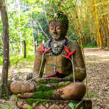 Ormanda, Kilauea, Kauai, Hawaii, ABD yakınlarındaki kolye ve çiçeklerle süslenmiş bir Buda heykeli..