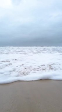 Kumsal, kum, dalgalar ve ayak izleri. 4K Yüksek çözünürlüklü video. 6 metre yüksekliğinde dalgalar. Ağır çekim. Sahilin kenarında sakin dalgalar ve dalgalar 6 metre yüksekliğinde dalgalar. Temiz plaj ve temiz su. Yüksek çözünürlüklü video, 4K. Yavaş çekim 2x