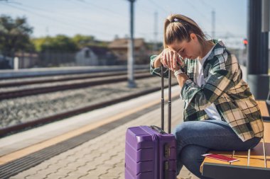 Tren istasyonunda bankta oturan endişeli kadın..