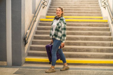 Tren istasyonundan geçerken elinde bavul ve biletle dolaşan mutlu kadın..