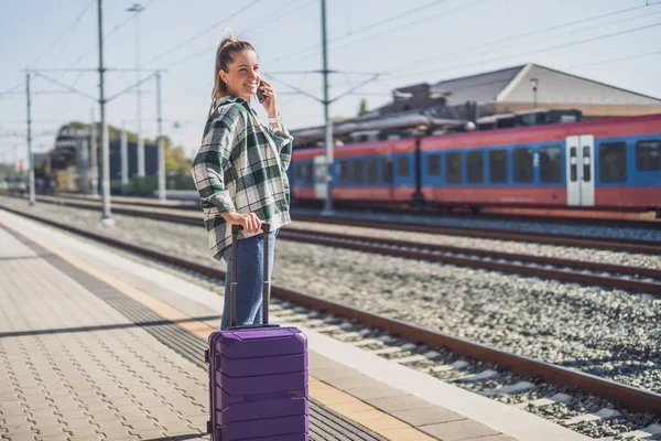 電車の駅で携帯電話を使う幸せな女性 — ストック写真