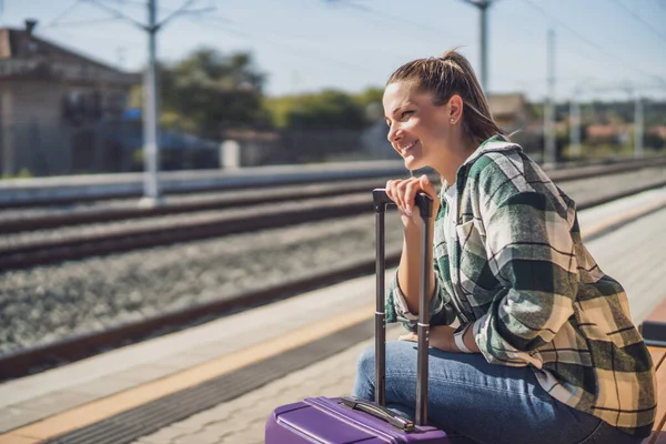 快乐的女人在火车站等火车时回头看去 — 图库照片
