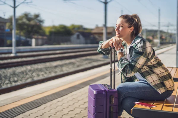 一个忧心忡忡的女人坐在火车站的长椅上 — 图库照片