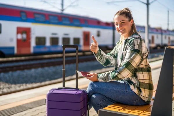 Szczęśliwa Kobieta Pokazuje Kciuk Górę Trzymając Bilet Siedząc Ławce Stacji — Zdjęcie stockowe