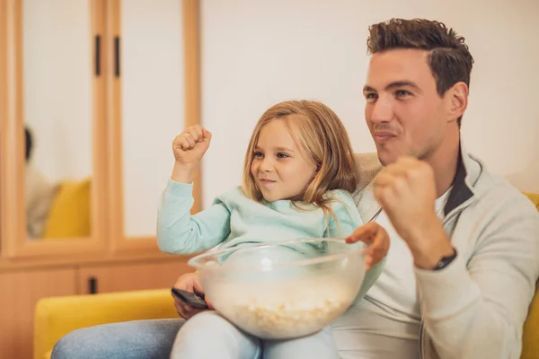 兴奋的父亲和女儿喜欢在家里看电视和吃爆米花 — 图库照片