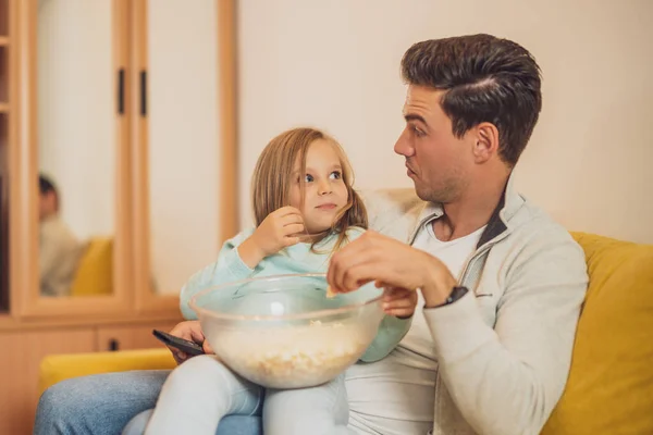 令人惊讶的父亲和女儿在家里看电视 一起吃爆米花 — 图库照片