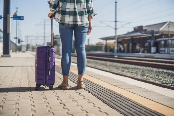 Woman with suitcase standing on train station.