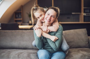 Happy mother and daughter enjoy spending time together at their home.