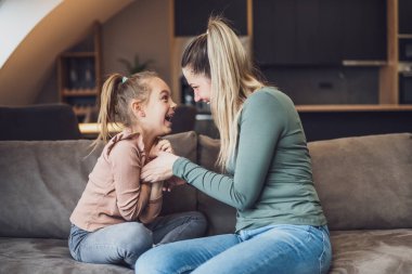 Happy mother and daughter enjoy spending time together at their home.