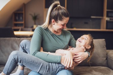Happy mother and daughter enjoy spending time together at their home.